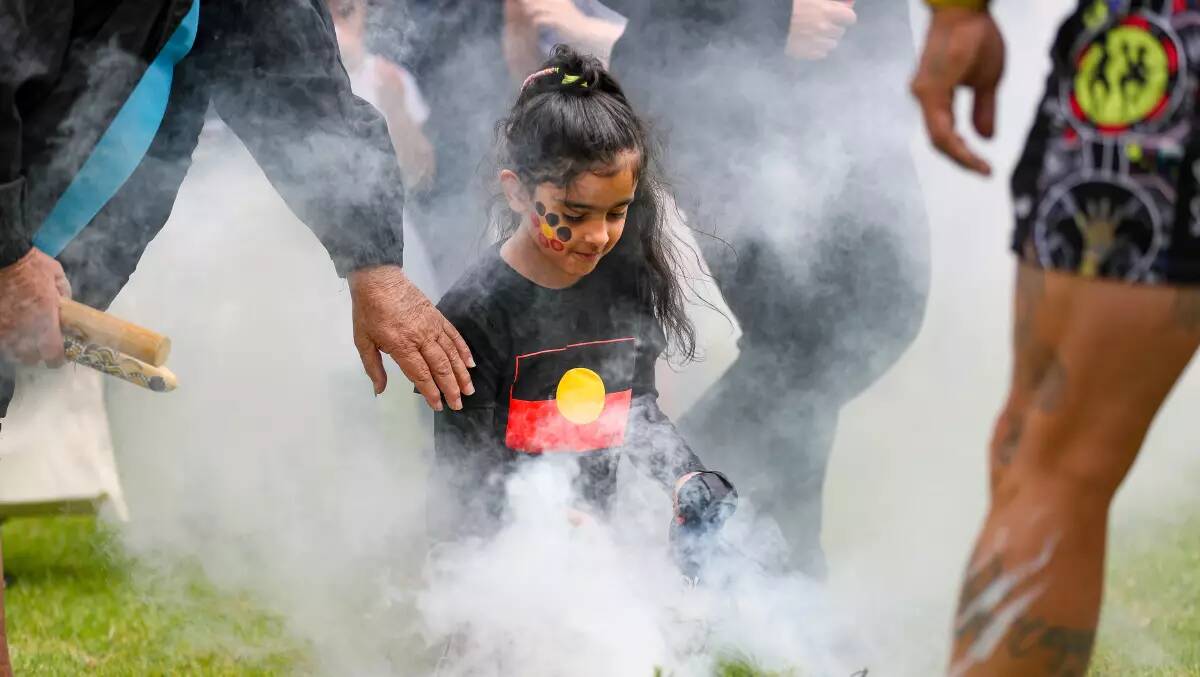 A file image of a young girl taking part in a smoking ceremony.