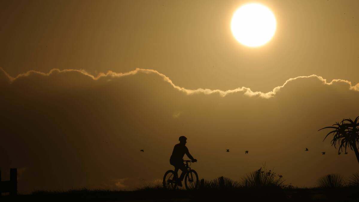 A person riding a bike at sunrise in Barrack Point. Picture by Sylvia Liber