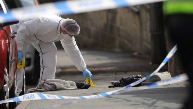 Forensic police examine shoes and a handbag at the scene. Photo: Getty Images
