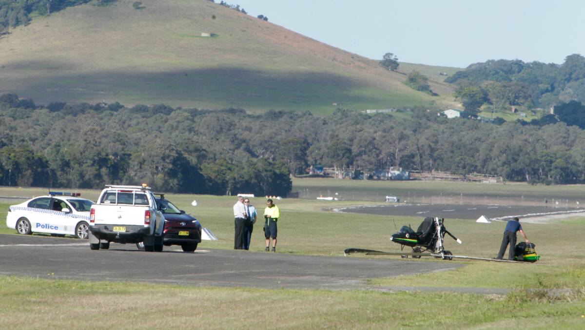 A man picks up a piece of the ultralight plane at the Albion Park airport. Picture: ADAM McLEAN