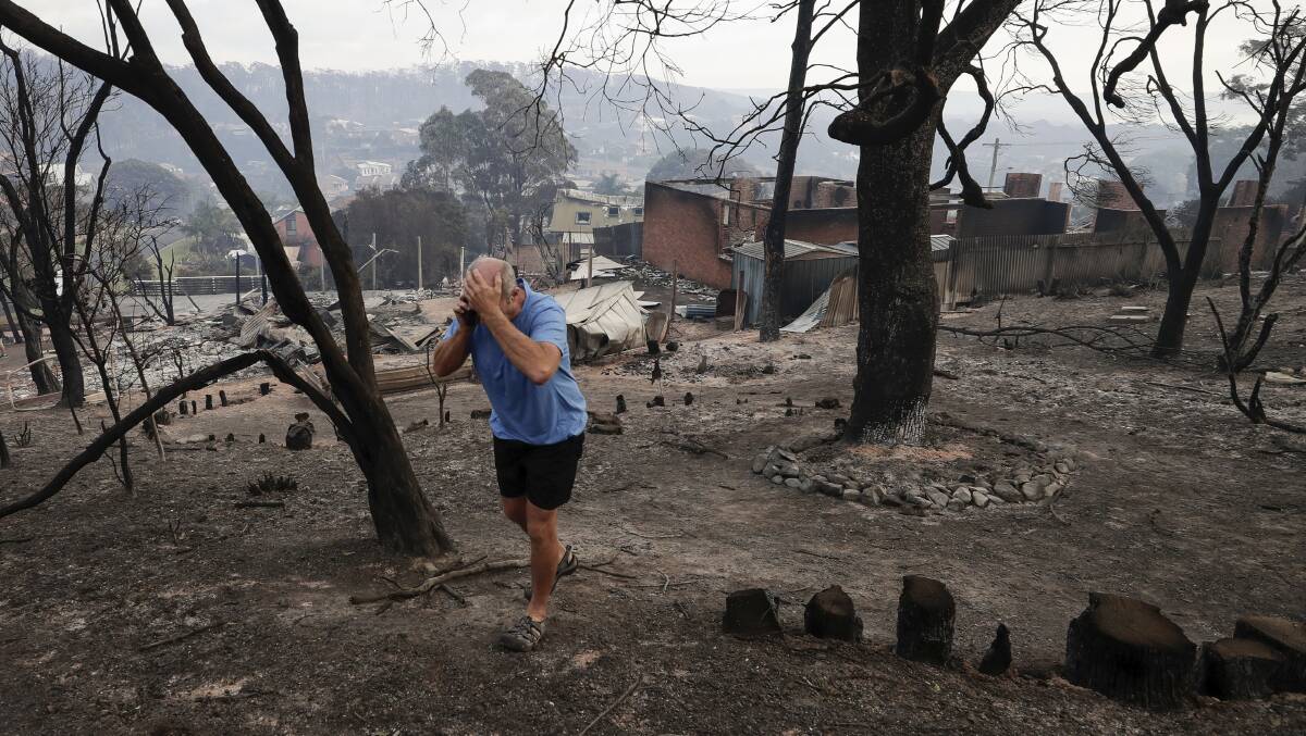 Tathra resident John Plumb on the mobile phone after viewing the aftermath of the Tathra bushfire. Picture: Alex Ellinghausen