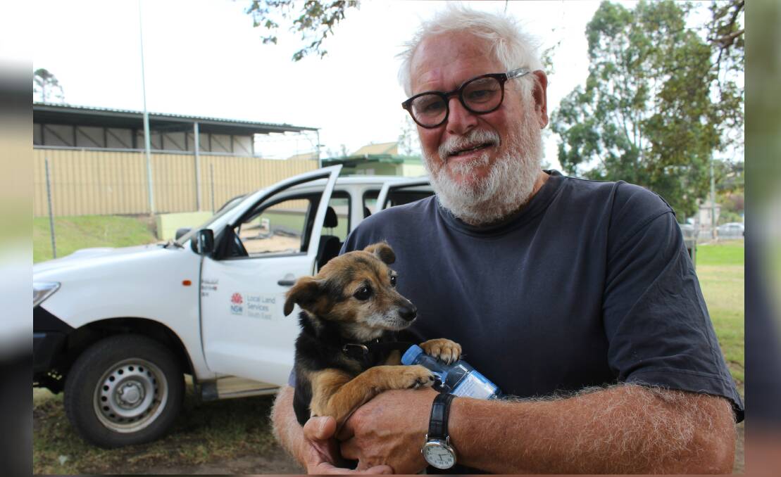 Peter Burgess holds a shaken but safe Milly after she was brought to the Bega Showgrounds by Local Land Services after two days alone in Tathra.