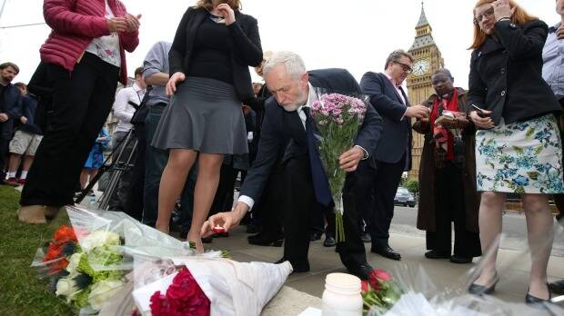 Labour Party leader Jeremy Corbyn, centre, lays a candle at an impromptu vigil at Parliament Square. Photo: AP