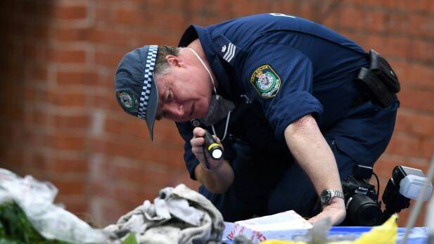 A police officer searches items from a property in Lakemba as part of an investigation into an alleged terrorism plot. Photo: AAP Image/Paul Miller
