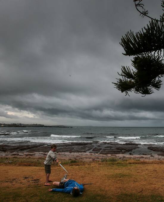 sword storm: Jack Martin and Ryan Donaldson in a sword fight at the Shellharbour Beachside Tourist Park as storm clouds build. Picture: Adam McLean 