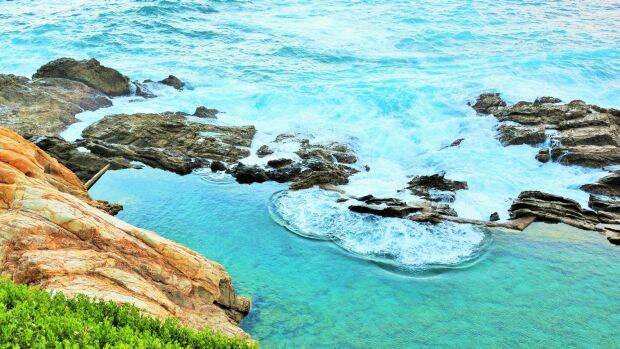 At the bottom of imposing cliffs, Bermagui's Blue Pools is a haven for families on a hot summer's day. Photo: Supplied

