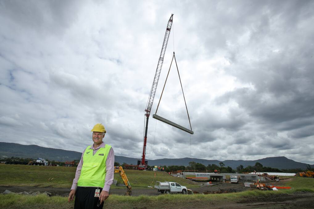 Road relief: Wollongong council's general manager David Farmer watches as 17-tonne concrete panels are lifted into place of the Fowlers Road bridge project. Picture: Adam McLean.