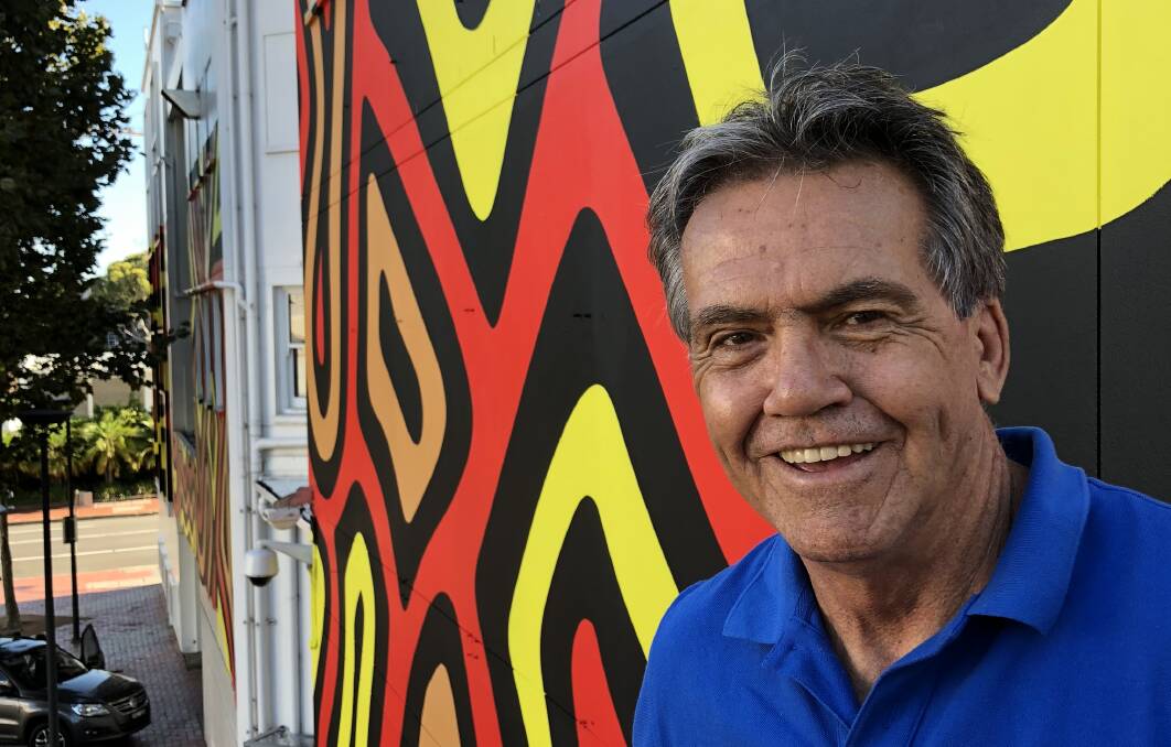 Indigenous artist Warwick Keen in front of a mural he designed which is currently being painted on the side of Wollongong Art Gallery. Picture: Supplied