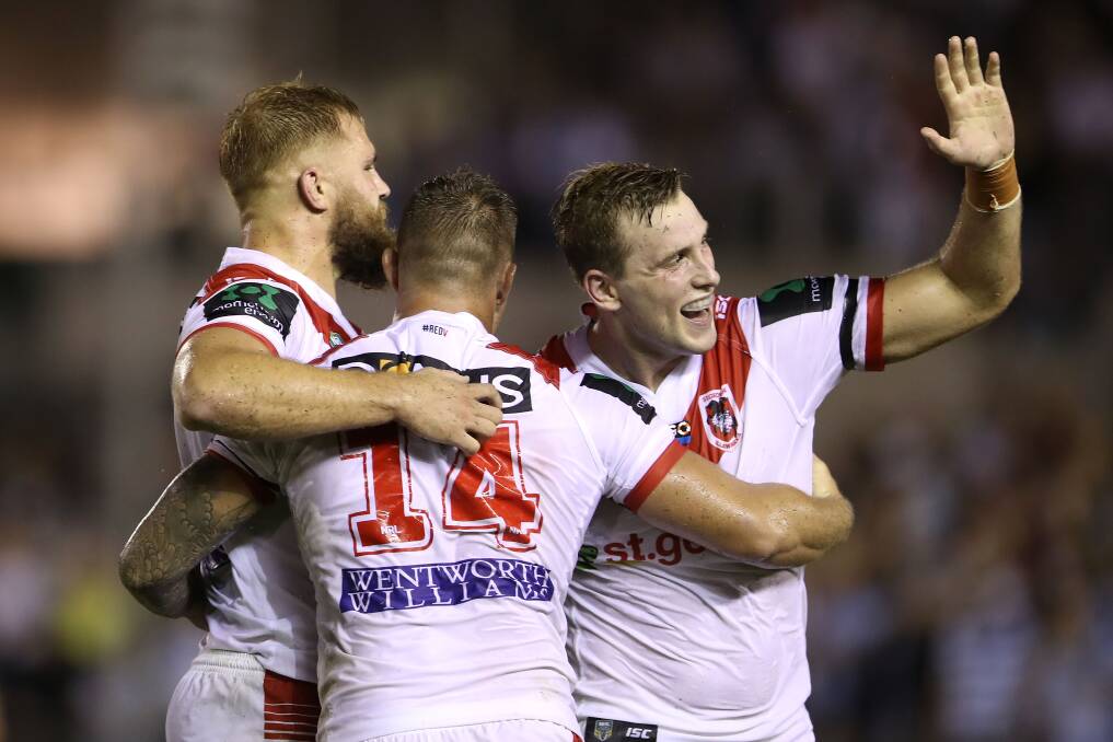 BIG WIN: Jack de Belin, Tariq Sims and Jacob Host embrace after the Dragons 16-10 victory over Cronulla on Sunday. Picture: Getty Images