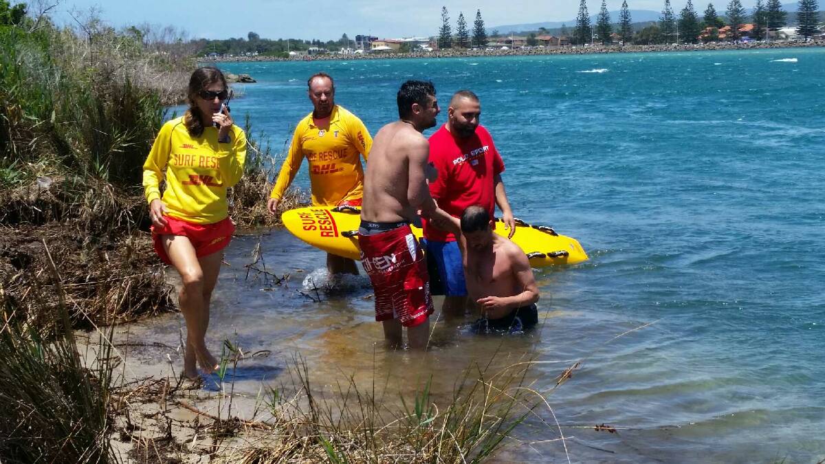 WEARY: Onlookers support a man pulled into a channel off Windang as lifesavers Kaye Norris and Doug Hockey and Alyssa Norris return to shore. Picture: Alyssa Norris