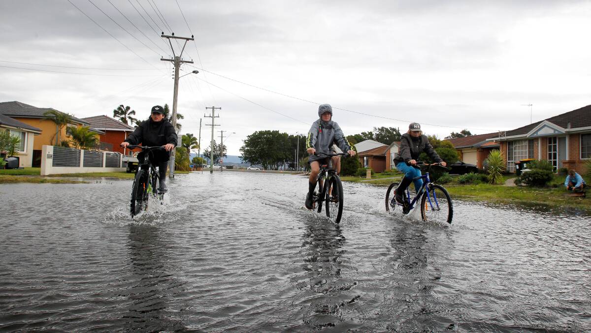 Curtis Petrovich Mason, Matthew Ryan and Jack Collison explore the newly inundated end of Boundary Road, Windang. Picture: Sylvia Liber