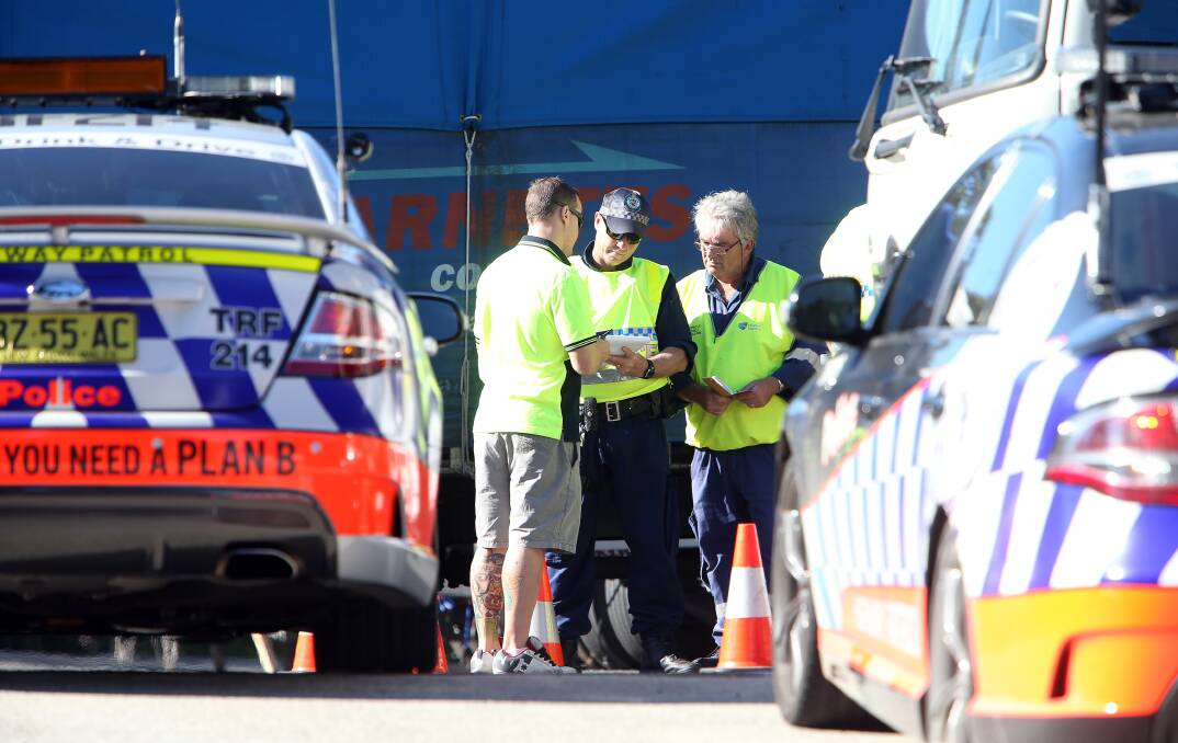 CHECKING: Police and roads authorities interact with a driver during an inspection of trucks at Barnetts Couriers Fairy Meadow headquarters on Friday. Picture: Sylvia Liber