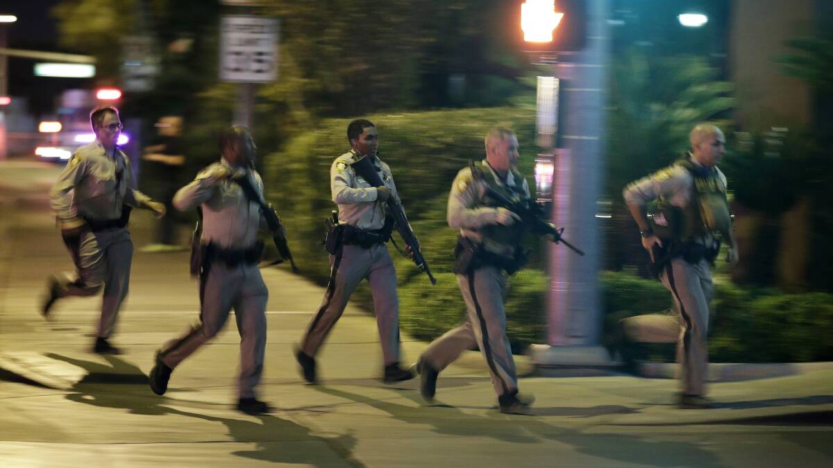 Police run to cover at the scene of a shooting near the Mandalay Bay resort and casino on the Las Vegas Strip. Photo: John Locher, AP