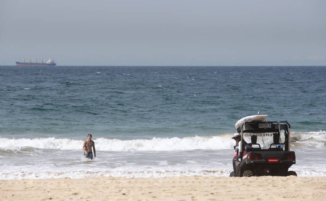 A lifeguard calls a swimmer in at closed North Beach, about midday. Picture: Adam McLean
