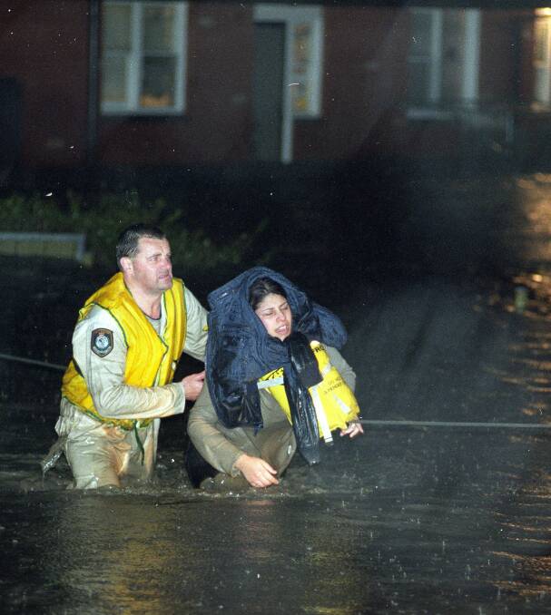 RESCUED: Senior Constable Gary Storey rescues Lina Cappetta from rising flood waters on Pioneer Road, Towradgi on August 17, 1998. Picture: Sylvia Liber