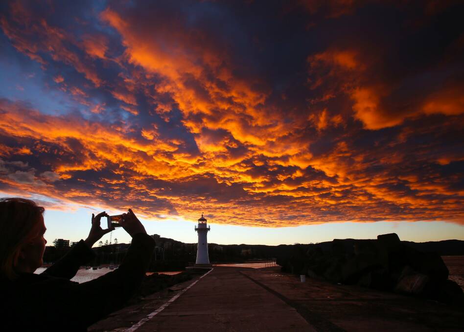Golden carpet: Wollongong's Flagstaff Hill lighthouse bathes in the reflected glory of a fiery sky from the west in this 2014 photo. Picture: Kirk Gilmour.