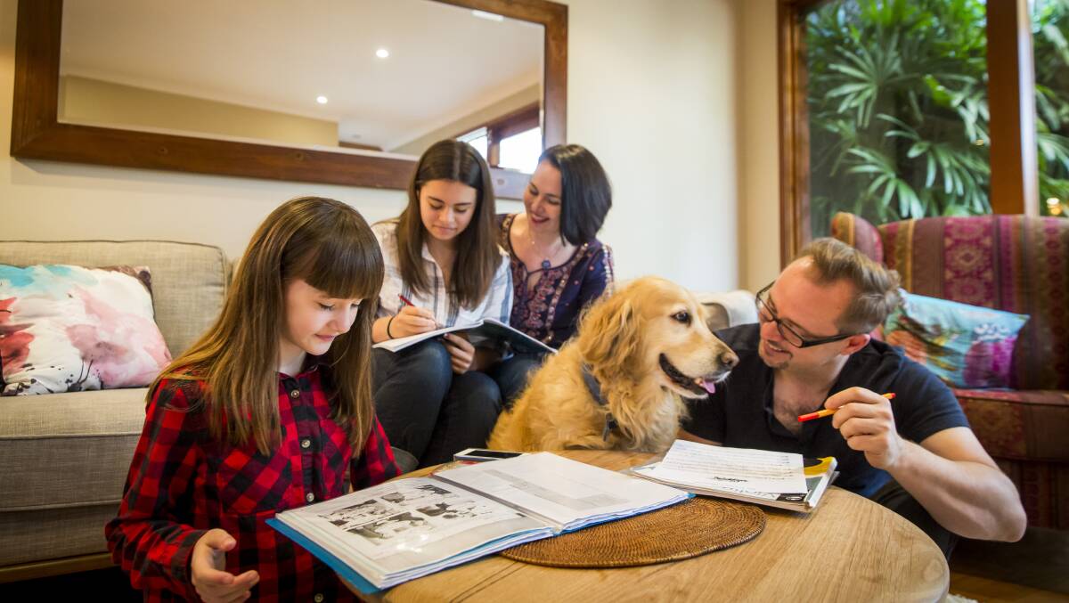 LAH-LAH AT HOME: Mark and Tina Harris helping their daughters with homework, Emily and Lily, plus Brodie the dog. Picture: Anna Kucera