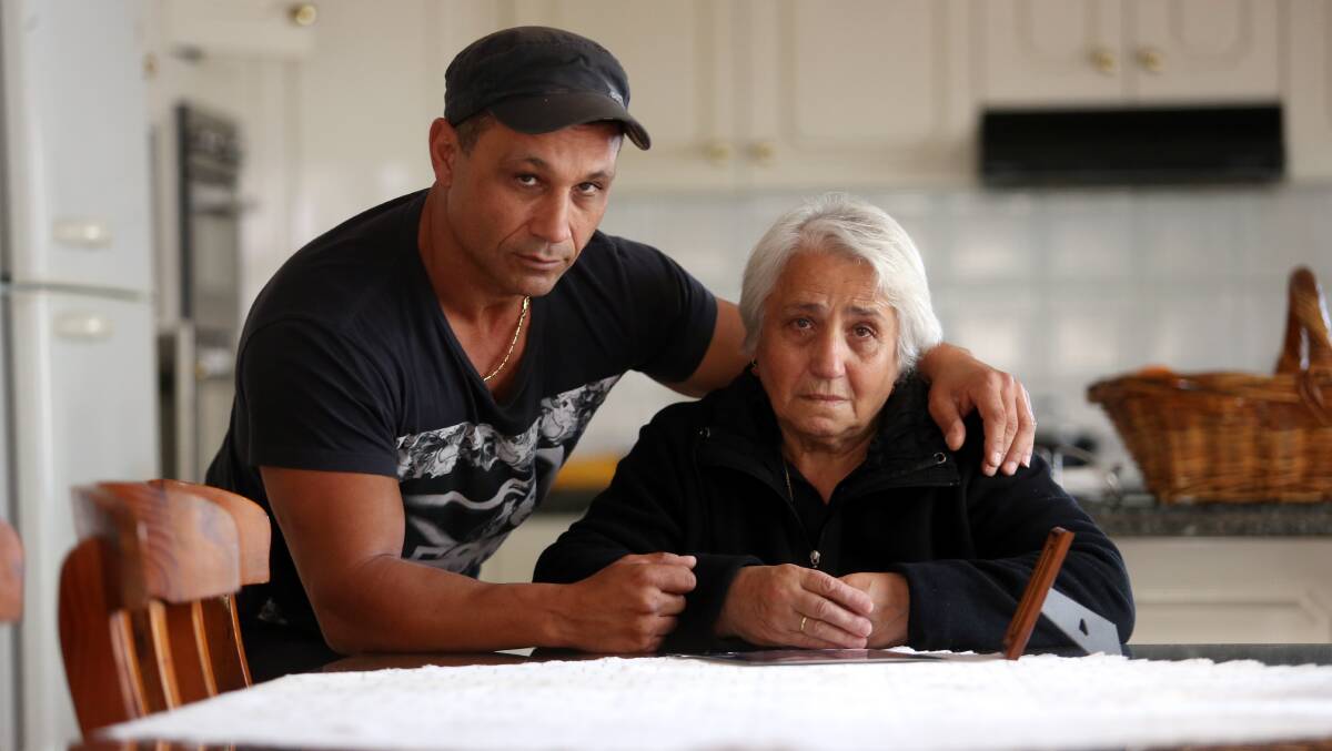 Ongoing grief: George Taousanis comforts his mother Theodora at her Shell Cove home as she comes to terms with the death of her husband Nick. Picture: Robert Peet