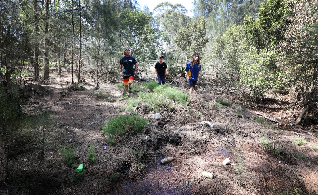 GROUND ZERO: Shaun Langlands with sons Sandom and Sage walking along Bensons Creek at Warilla, with rubbish clearly visible.