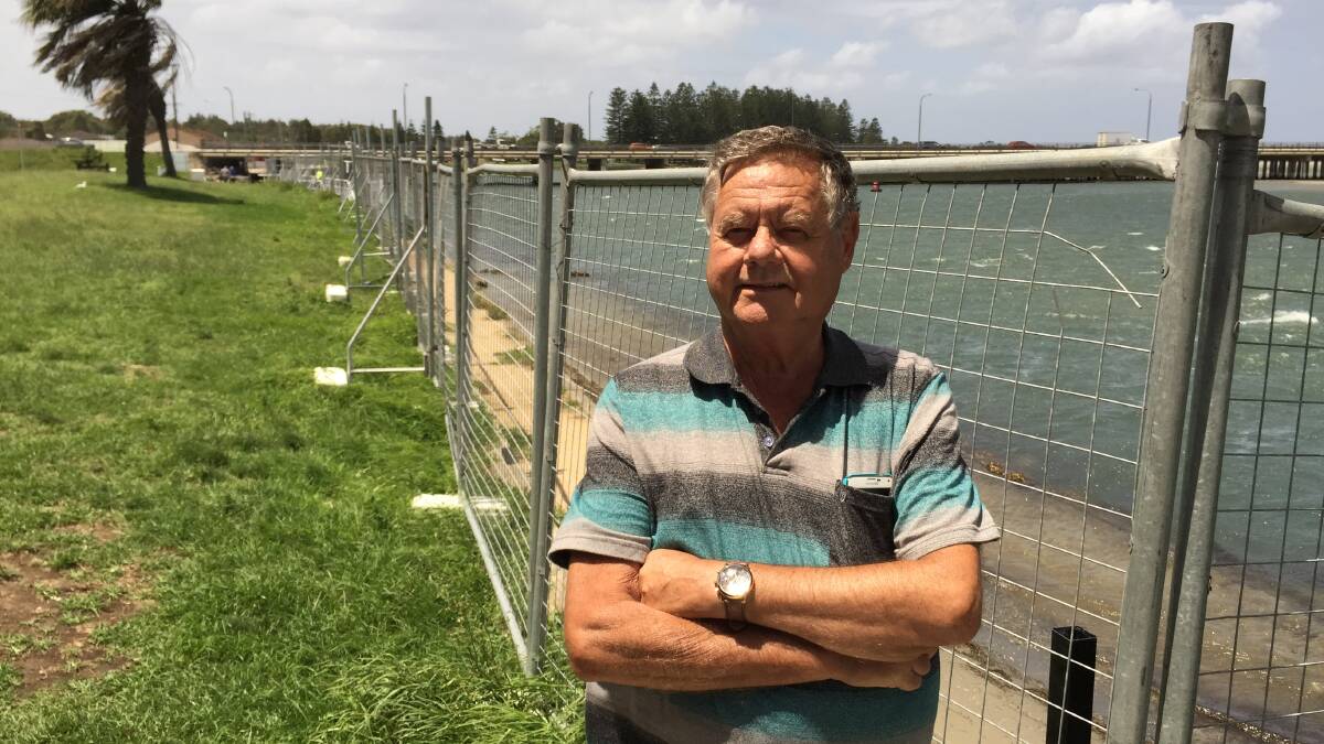 Ian Gibb stands against the cyclone fencing blocking off the eroding sea wall at Windang. Picture: Ben Langford