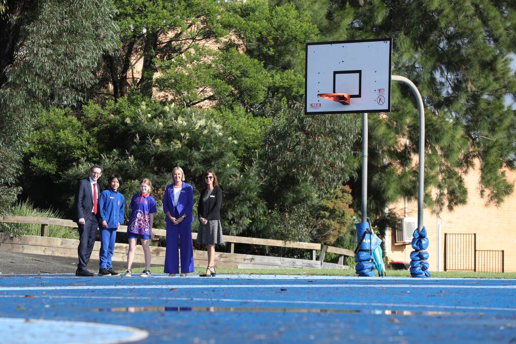 Whitlam MP Stephen Jones, Barrack Heights Public School leaders An Nguyen and Annabel Harris, principal Skye Ramsay, and Karen Brown from the NSW Department of Education on the basketball court which is in line to receive a shelter overhead. Picture by Robert Peet