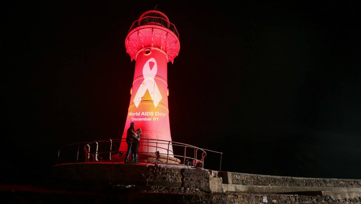 All lit up: On Saturday night Melina Rinses and David Frith danced in the light of the old lighthouse at Wollongong Harbour, which was lit up to acknowledge World AIDS Day. Picture: Adam McLean