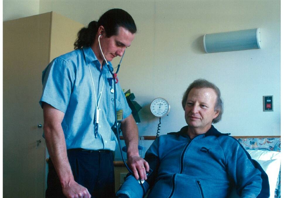 Wonder years: The hospital CEO sporting a ponytail and a stethoscope with a patient at the start of his career at the Figtree hospital. Picture: Supplied