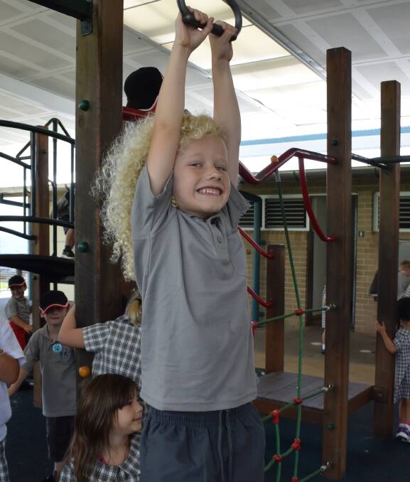 HANG TIME: Port Kembla Public School kindergarten student Quade Wood on the play equipment at his first day of school. Pictures: Agron Latifi.