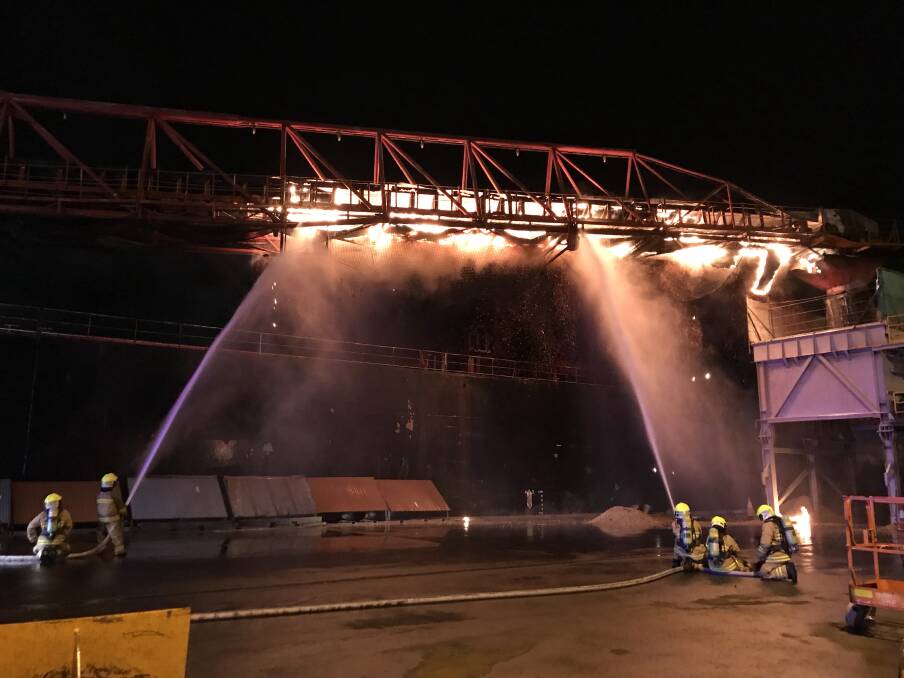HARD TO GET AT: Firefighters train hoses on a conveyor belt attached to the Iron Chieftain, in the early stages of the firefighting effort last week. Picture: Supplied