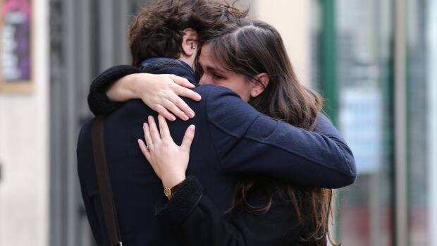 A couple embrace after laying flowers at the La Belle Equipe cafe in Paris Photo: Andrew Meares