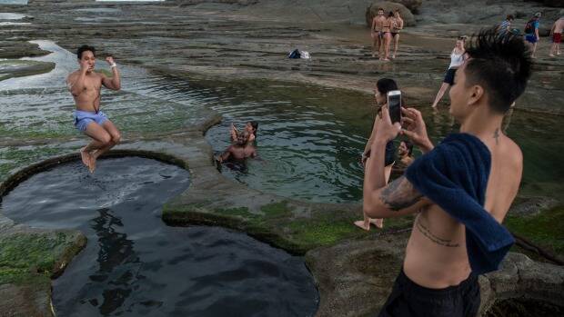  Tourists pose for photographs earlier in January at the Figure Eight Pools in the Royal National Park. Photo: Wolter Peeters