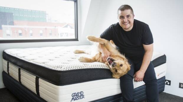  OzMattress owner Stefan Papas with his dog Mac on one of the mattresses manufactured by his company. Photo: Craig Sillitoe