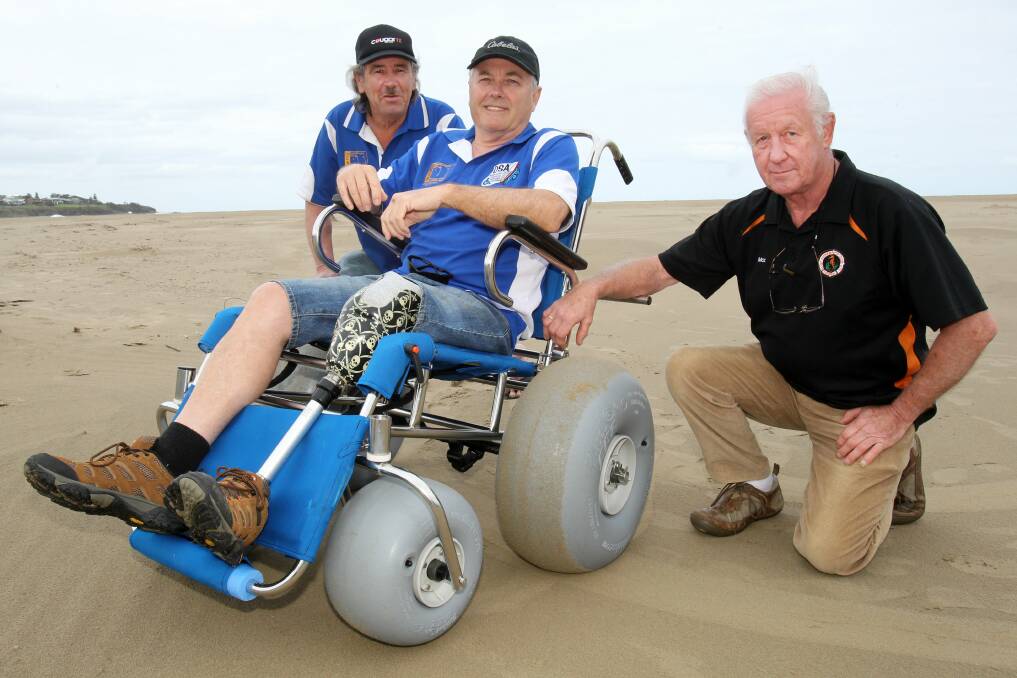 Cecil Campbell, left, and James Smith from the Disabled Surfers Association, and Ian McDermott of Gerroa Fisherman's Club at Gerroa for the hand-over of a Sandcruiser wheelchair. Picture: GREG TOTMAN