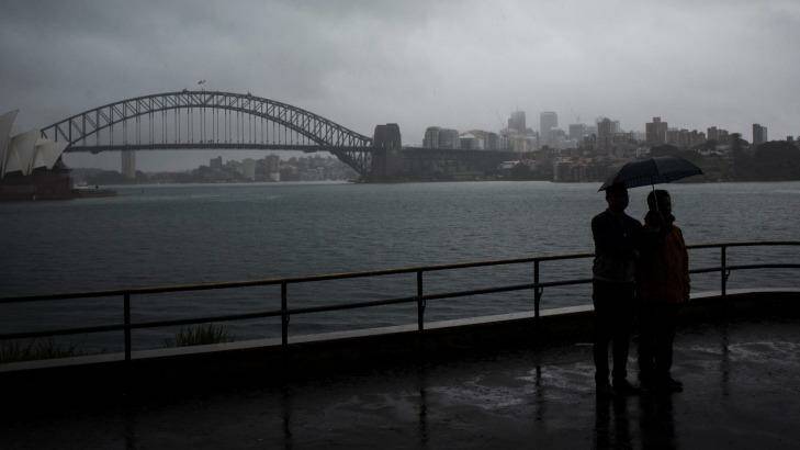 Tourists huddle under an umbrella as rain hits Sydney on Wednesday. Photo: Dominic Lorrimer