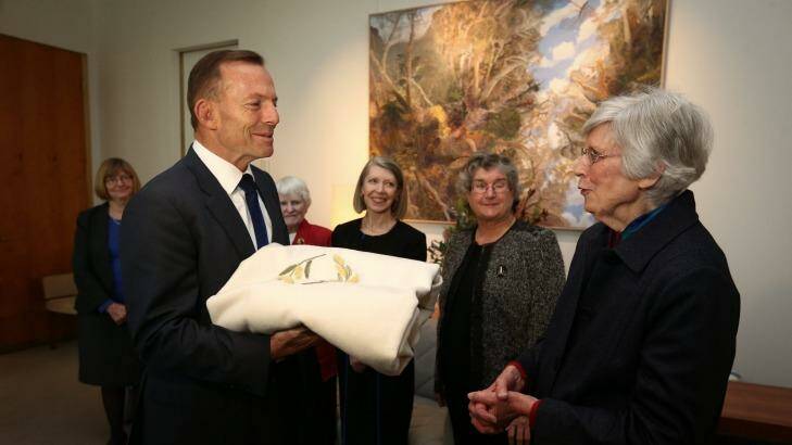 Prime Minister Tony Abbott meets with Audrey Schultz and members of the ACT Embroiderers' Guild to view the baby blanket. Photo: Alex Ellinghausen