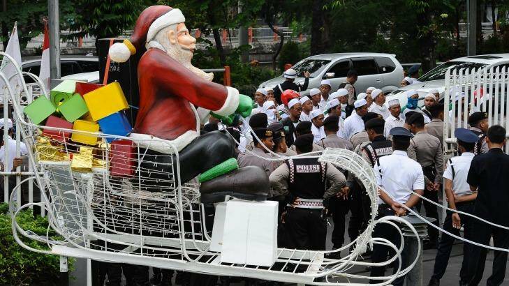 A Santa on a sleigh is seen near a protest against Christmas apparel by members of the hardline Islam Defenders Front in Surabaya. Photo: Robertus Pudyanto