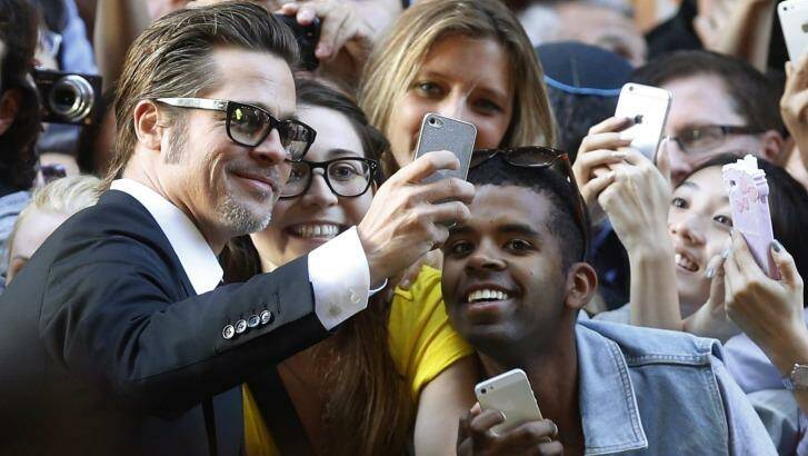 Brad Pitt spends some time taking selfies with fans at the Unbroken premiere in Sydney.  Photo: Jason Reed/Reuters