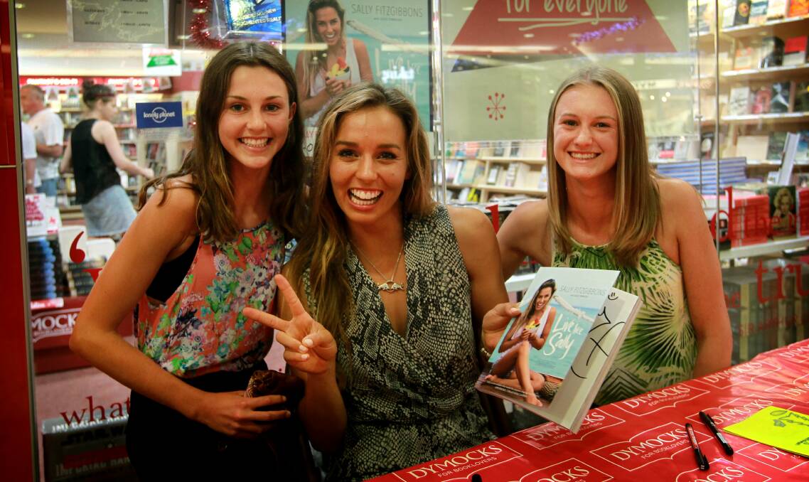 Sally Fitzgibbons at her book signing on Thursday with Warilla sisters Brook Cavanagh, 13, left, and Ashley Cavanagh, 15. Picture: SYLVIA LIBER