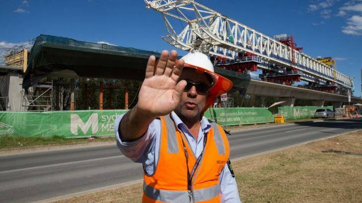 A security guard attempts to stop photographs of the buckled span on the Skytrain viaduct in Sydney's north-west. Photo: Janie Barrett
