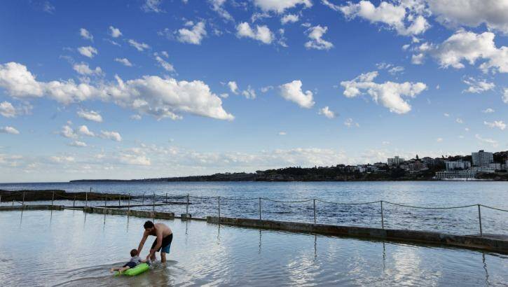 A man enjoys the exceptionally warm weather and plays with his son at the kids pool at North Bondi. Photo: Jessica Hromas