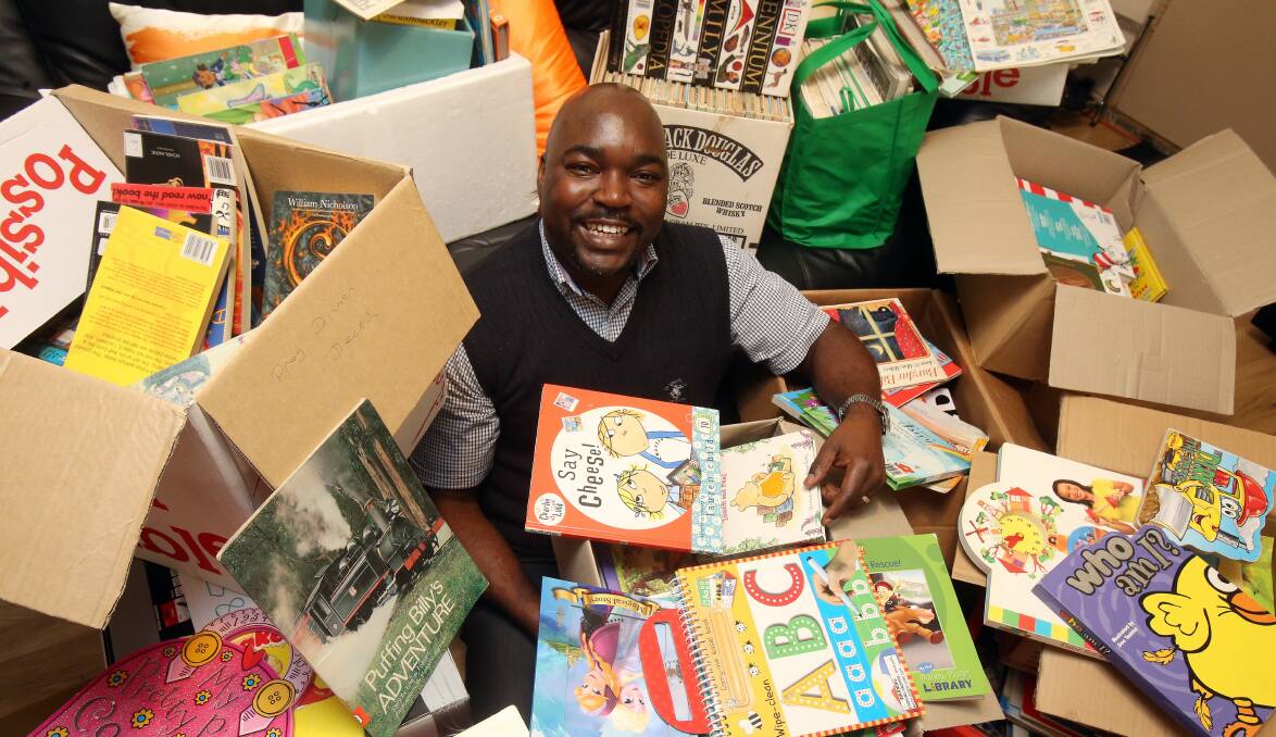 Booked in: Dr Alfred Chidembo is buried in books he has been collecting for his village in Zimbabwe.Picture: ROBERT PEET