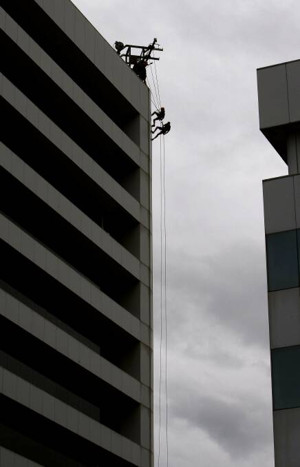 The pair make their way down the 45m high building. Picture: ANDY ZAKELI