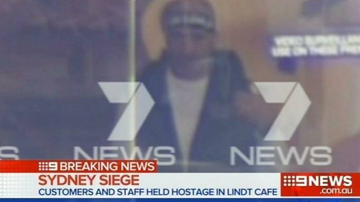Man Haron Monis seen through the glass of the Lindt cafe. Photo: Channel Seven
