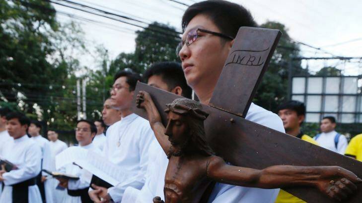 A Catholic priest carries a wooden crucifix during a prayer vigil held last month to protest against the killings in the Philippines as President Duterte pursues his war on drugs.  Photo: Bullit Marquez/AP