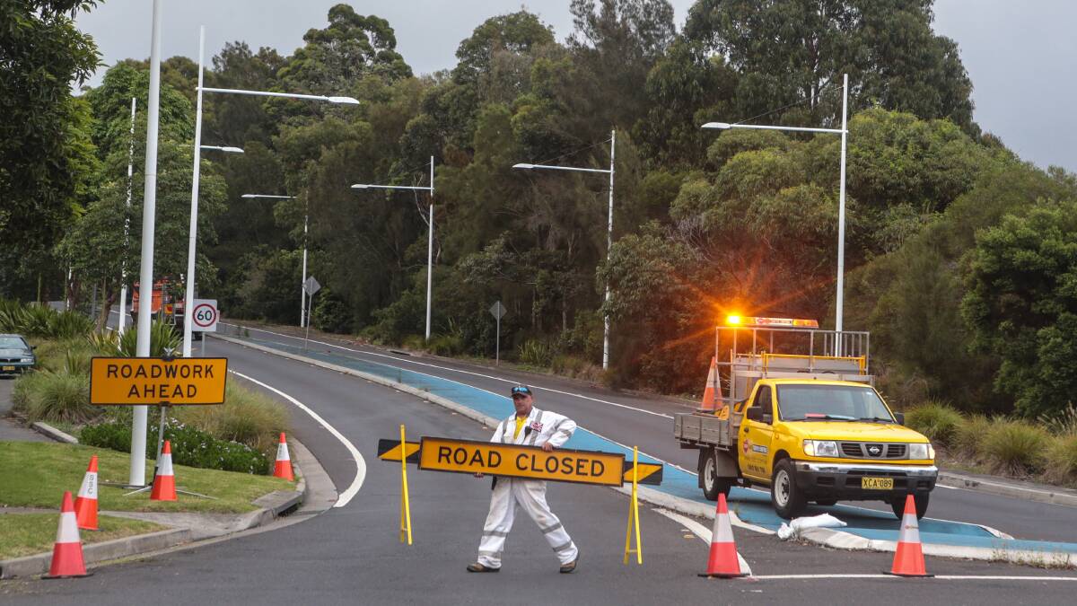 No exit: A road worker closes the Mt Ousley Road exit lane at the intersection of Mt Ousley Road and Gaynor Avenue. Picture: ADAM McLEAN