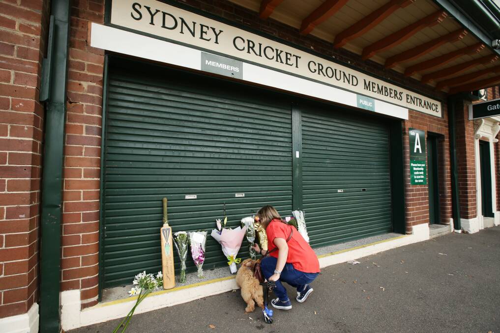 A woman leaves flowers at the Sydney Cricket Ground members' entrance as a tribute to Phillip Hughes.Picture: GETTY IMAGES