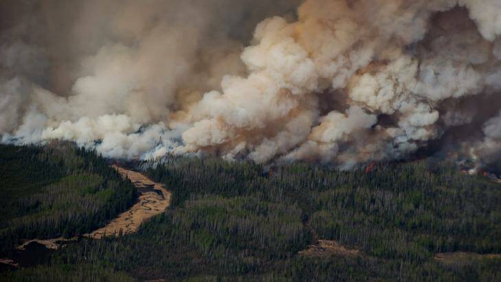 Smoke rises from Canadian wildfires burning near Fort McMurray, Alberta as the fire season started a month early this year. Photo: Darryl Dyck, Bloombeg