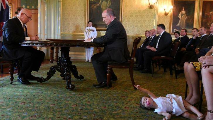 David Elliott, new Minister for Counter Terrorism, signs an oath at Government House as John Barilaro's daughter Sofia plays at her mother's feet. Photo: Peter Rae