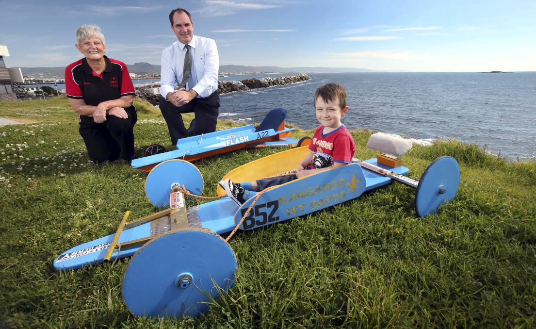 Dulcie Dal Molin, Red Point Artists Association president, and Kell Dillon, from the Port Authority of NSW, with Domonik Gomboso in his billycart at Port Kembla heritage Park. Picture: KIRK GILMOUR