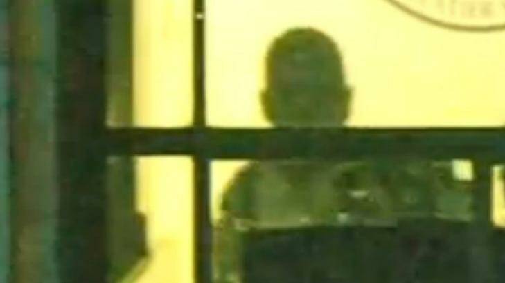 Gunman Man Haron Monis seen through a window of the Lindt cafe. Photo: Channel Seven
